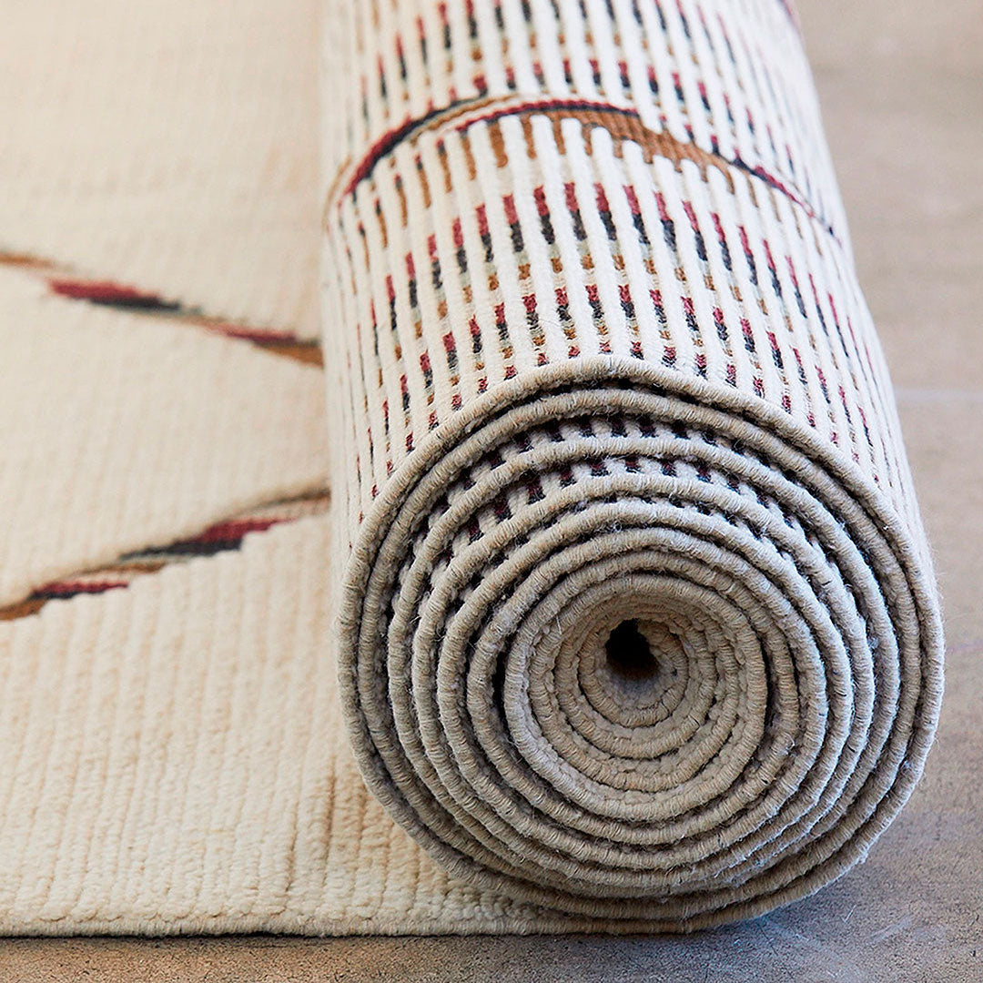 Rolled-up patterned rug on a neutral background